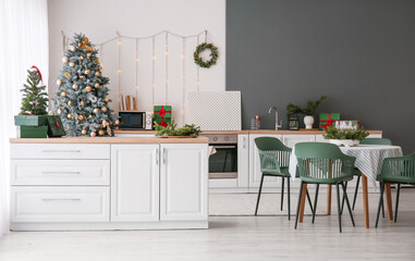 Interior of kitchen with Christmas trees, counters and dining table