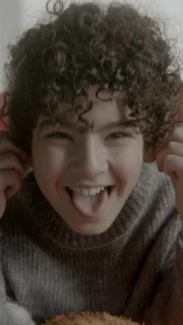 Children sitting on a red sofa, boy pulling silly faces
