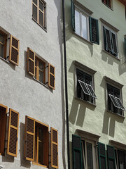 Old historic architecture in Italy. Traditional European old town building. Wooden windows, shutters and colourful pastel walls with sunlight shadows. Aesthetic summer vacation travel background