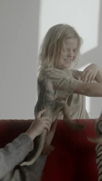 Three boys playing with dinosaur toys sitting on a red sofa