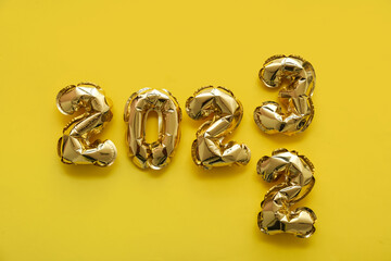 Figure 2022 made of balloons replaced by 2023 on yellow background