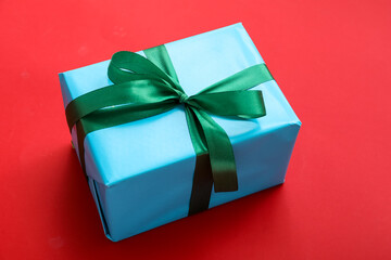 Beautiful Christmas gift tied with ribbon on red background