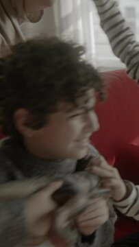 Three boys playing with dinosaur toys sitting on a red sofa