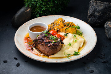 Fresh filet mignon beef steak with mashed potatoes, corn, tomatoes and sauce.