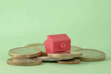 Casa junto a dinero, montaña de monedas de euro, inflación y subida de Euribor