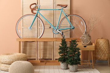 Interior of living room with bicycle, shelf and small fir trees
