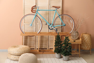Interior of living room with bicycle, shelf and small fir trees
