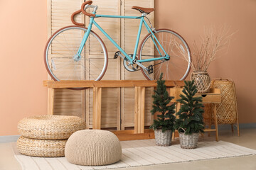 Interior of living room with bicycle, shelf and small fir trees