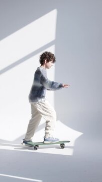 two children skateboarding in a white room