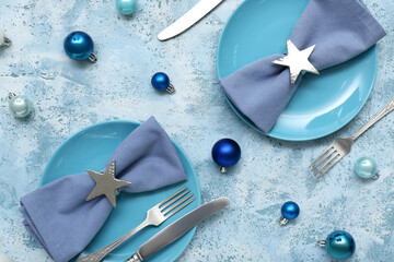 Beautiful table setting with blue plates and Christmas balls on grunge background