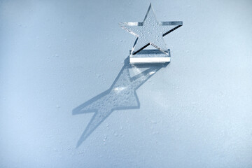 A prize made of glass in the form of a five-pointed star on a silver background in raindrops. A...