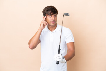 Young golfer player man isolated on ocher background having doubts and thinking