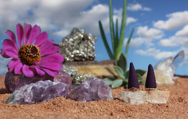 Fototapeta na wymiar Chakra Stones and Flowers on Australian Red Sand