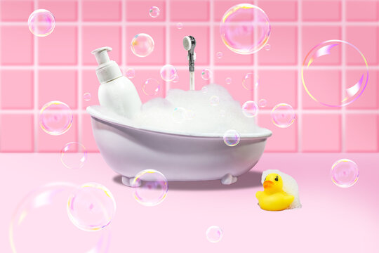 White bath with foam and soap bubbles, with a yellow duck and a bottle of cosmetic product on a pink background. Concept photo.