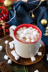 Christmas winter cozy cup hot chocolate drink with marshmallow and christmas lights, sweater knitted on a wooden background. Christmas drink concept.