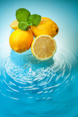 Juicy lemons with mint on a blue background with water splashes.