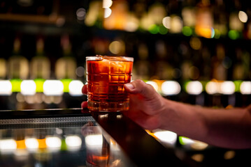 male hand holding a glass of coktail in a bar