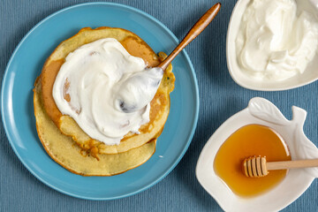 Fresh honey and cream cheese for Moroccan crepe Mofletta on blue background.