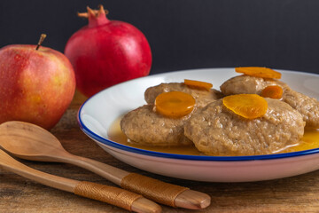Gefilte fish served with carrot in ceramic bowl on the background of fresh fruits for Jewish holiday Pesach or Passover.