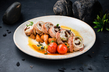 Chicken rolls in bacon with pesto sauce and sun-dried tomatoes in a plate.