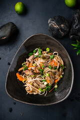 Udon noodles with teriyaki beef and vegetables: red pepper, tomatoes, onion and sesame seeds.