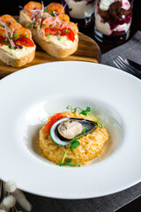 Italian food Risotto with mussel, red caviar and green peas on the background of bruschetta and desserts.