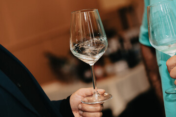 Glass of white wine held by a person at a premium wine tasting with friends and loved ones.