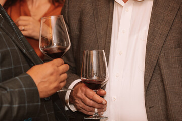Glass of red wine held by a person at a premium wine tasting with friends and wine lovers.