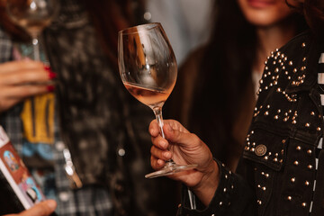 Glass of rose wine held by a person at a premium wine tasting with friends and loved ones.