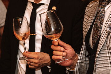 Glass of rose wine held by a person at a premium wine tasting with friends and loved ones.