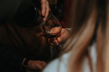 Glass of red wine held by a person at a premium wine tasting with friends and wine lovers.