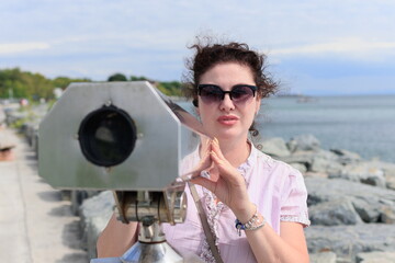 Brunette woman looking through binoculars for a panorama of the sea and ships