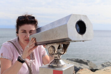 Brunette woman looking through binoculars for a panorama of the sea and ships