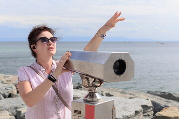 Brunette woman looking through binoculars for a panorama of the sea and ships
