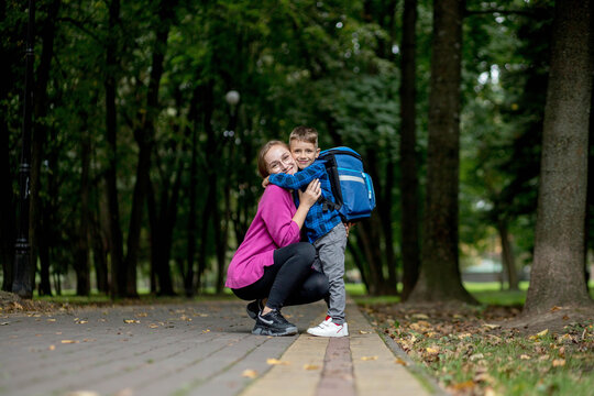 Young mother embraces her excited first class son on the way to school. Ready to study