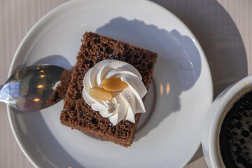 Chocolate shortcake with whipped cream for coffee drinks on white plate.
