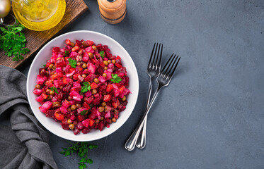 Traditional salad vinaigrette on a dark background. Salad with vegetables, peas and fresh herbs. Top view, copy space.
