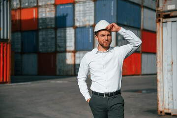 Beautiful portrait. Male worker is on the location with containers