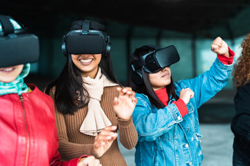 Young multiracial girls using futuristic virtual reality glasses - Technology and metaverse concept