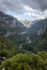 Fototapeta na wymiar Valley in Yosemeti National Park with conifers, low clouds, cloudy sky and patches of fog, California, USA 