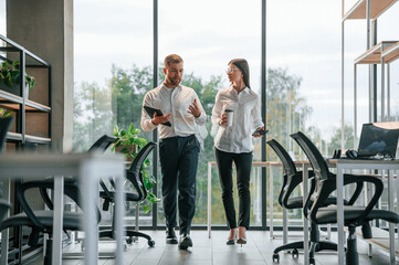 With tablet and drink. Man and woman are working in the modern office together