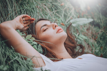 Young woman lying on the grass. Beauty woman lying on the field and looking on camera. Beautiful brunette Girl lying on the meadow, relaxing. Enjoying nature. Spring or Summer Green Grass. Freedom - 545407183