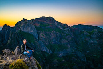 Man in leather jacket enjoying the scenic evening atmosphere of mountain terrain in the valley on...