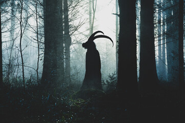 A fantasy concept of a pagan horned goat like figure. Silhouetted against the light. In a spooky forest in winter. With a textured edit.