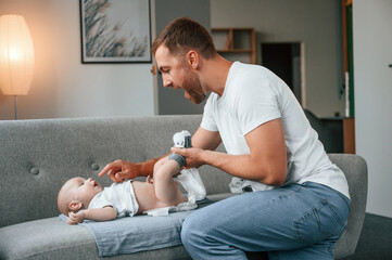 Father with toddler is at home, taking care of his son. Changing diapers