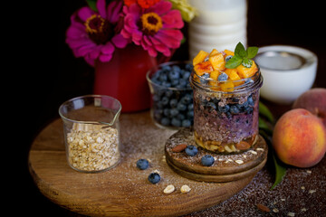 Obraz na płótnie Canvas Homemade granola, muesli with blueberry and yogurt in glasses on rustic wooden background. Healthy breakfast.