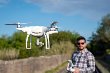 Hombre con lentes jugando con su drone en vuelo. Fotografía con enfoque selectivo en el drone
