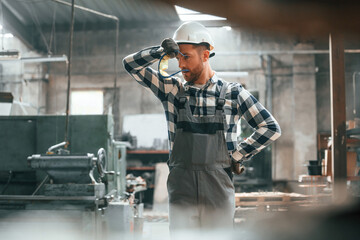 Tired factory male worker in uniform is indoors