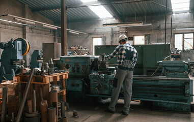 Fototapeta na wymiar Back view. Factory male worker in uniform is indoors