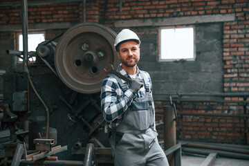 Fototapeta na wymiar Big wrench in hand. Factory male worker in uniform is indoors
